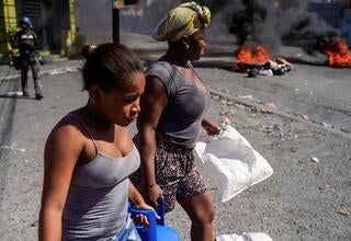 Women carry containers of propane gas … 3 of hospitals reported to be closed .. © RICHARD PIERRIN/AFP via Getty Images