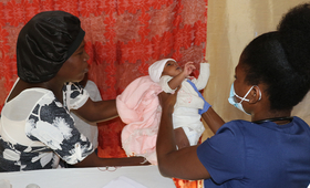 A midwife treating a baby in the presence of his mother