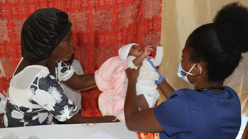 A midwife treating a baby in the presence of his mother